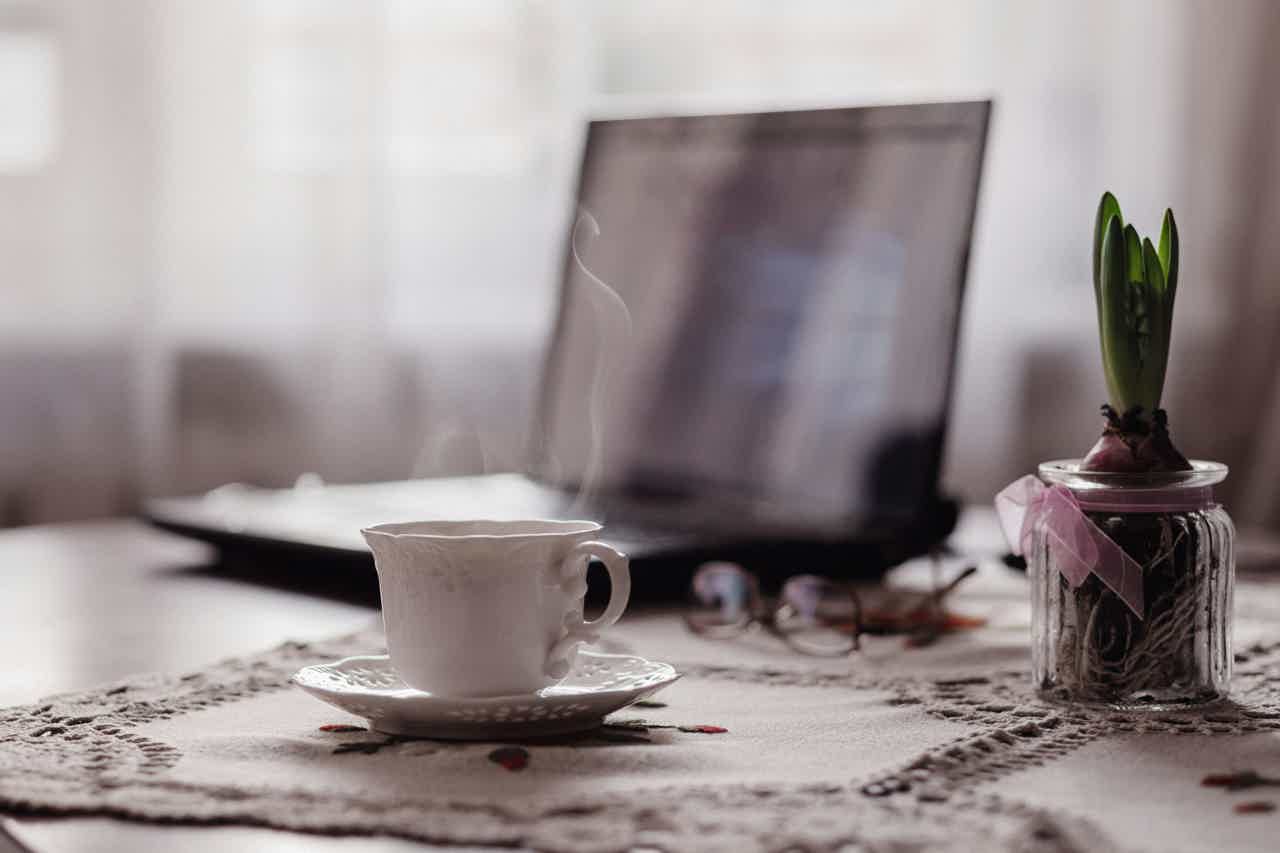Steaming mug on table next to open laptop
