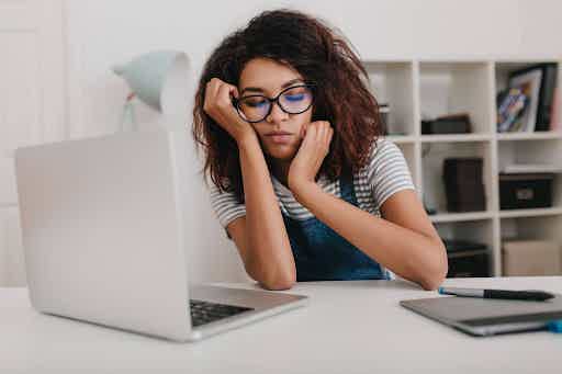 Exhausted woman resting her head in her hands at her desk.