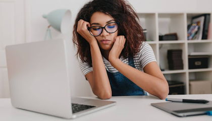 Exhausted woman resting her head in her hands at her desk.