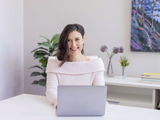 Dr. Andrea Gri, ND, smiling at her desk with a laptop