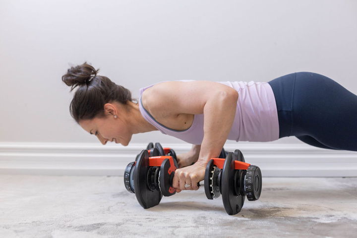 Dr. Andrea Gri, ND, holding a plank position with dumbbells