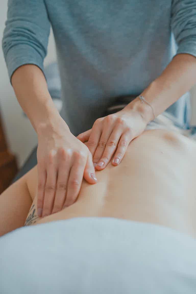 A therapist performing a back massage on a client in a serene spa setting.