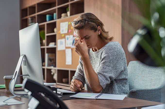 Woman at her desk pinching the bridge of her nose, struggling with focus and mental fog.

