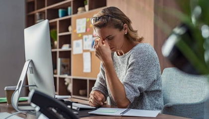 Woman at her desk pinching the bridge of her nose, struggling with focus and mental fog.
