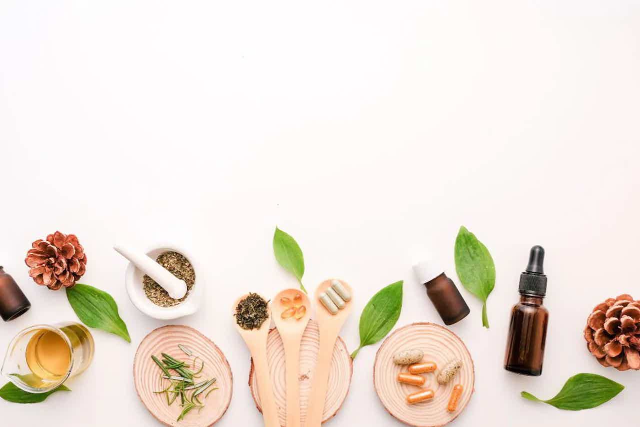 Fresh herbs, lemon slices, and small bowl of black pepper on white rustic wooden table, overhead view.
