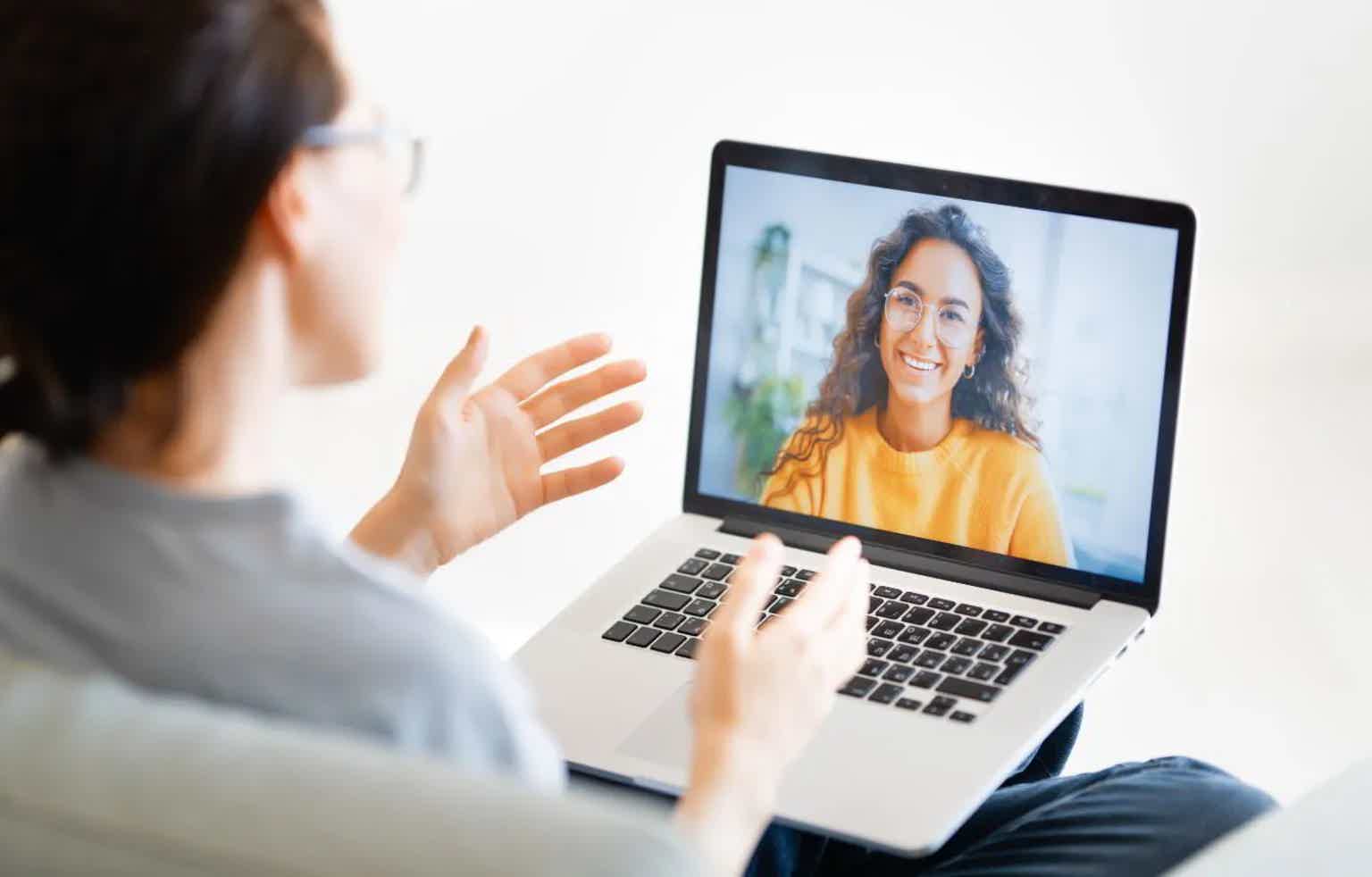 Woman video-chatting on a laptop screen, smiling person visible during a call.