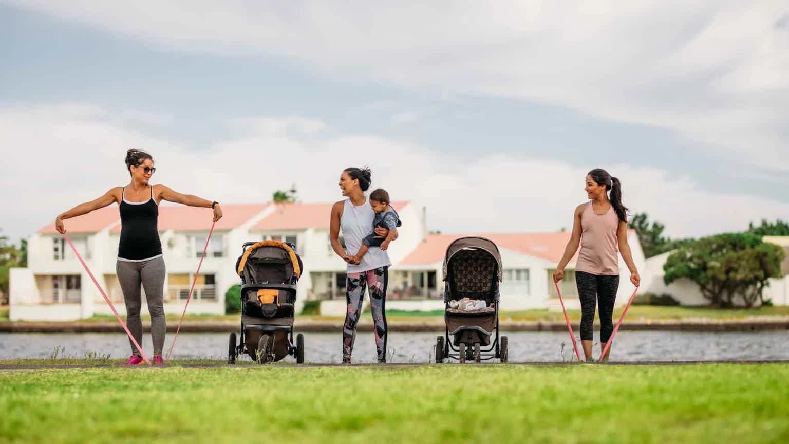 Four women exercise with resistance bands outdoors beside treadmills on a lawn, with houses and trees in the background.