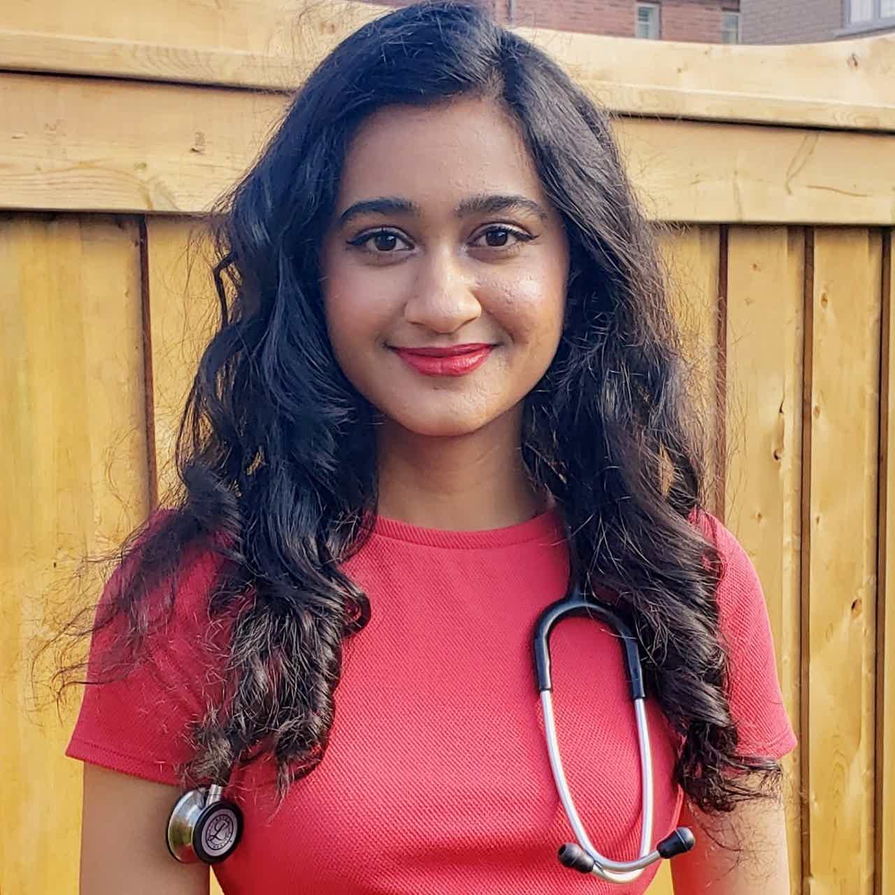 Smiling woman with wavy brown hair sits on brown leather couch, holding a teal mug, in a cozy living room.