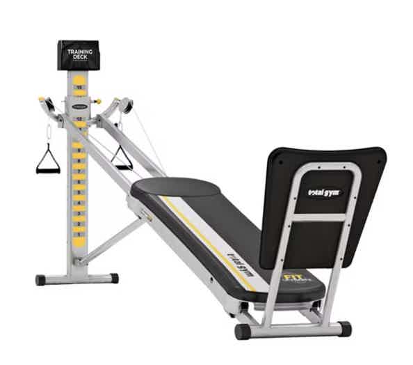 White Total Gym exercise machine with yellow frame markings and a padded incline seat.