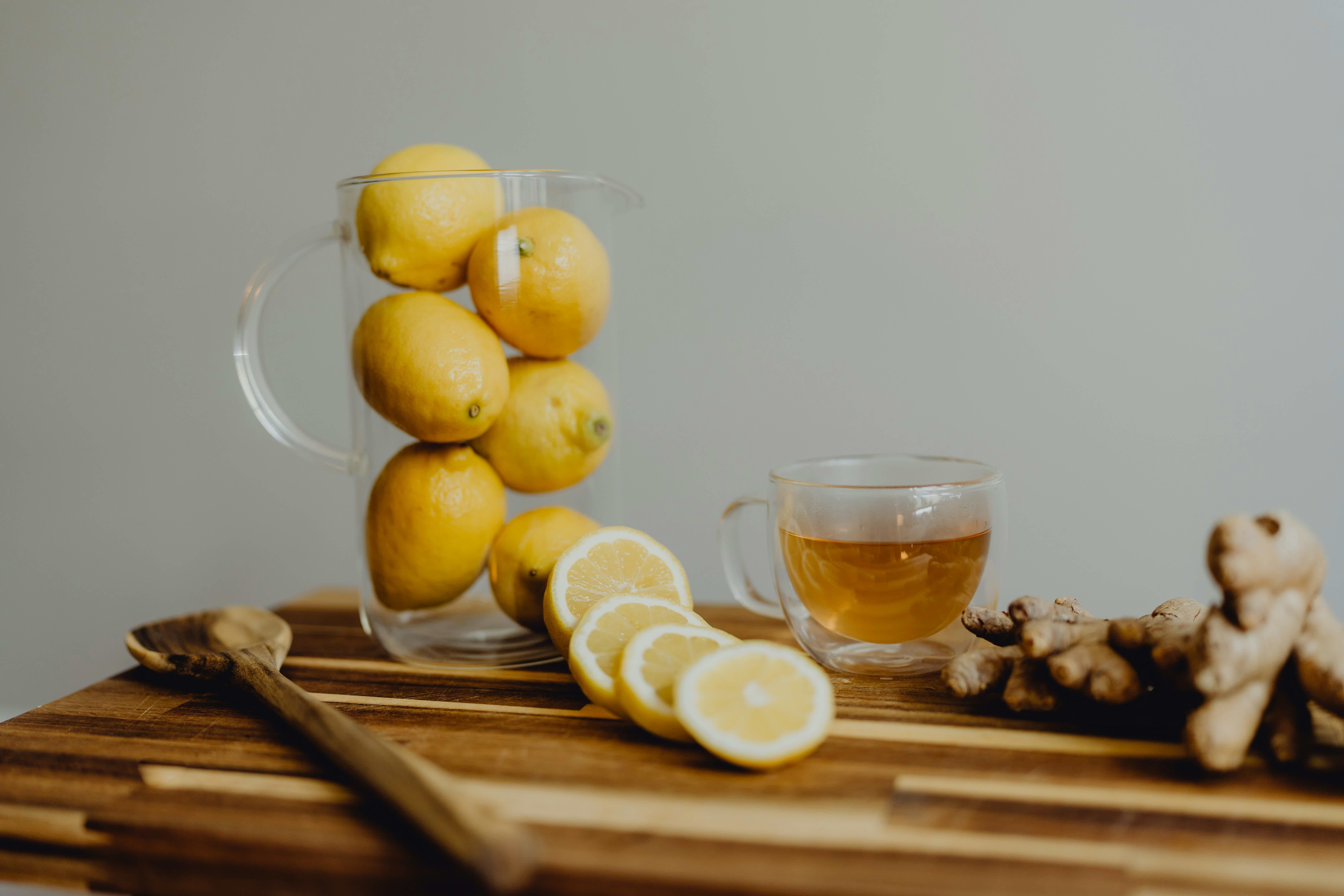 a wooden cutting board topped with lemons and a cup of tea