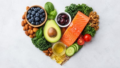 Heart-shaped arrangement of heart-healthy foods including salmon, avocado, nuts, blueberries, and leafy greens.