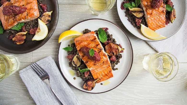 Pan-seared salmon over lentils with figs and mint, plated as a hormone-supporting, omega-3-rich meal.