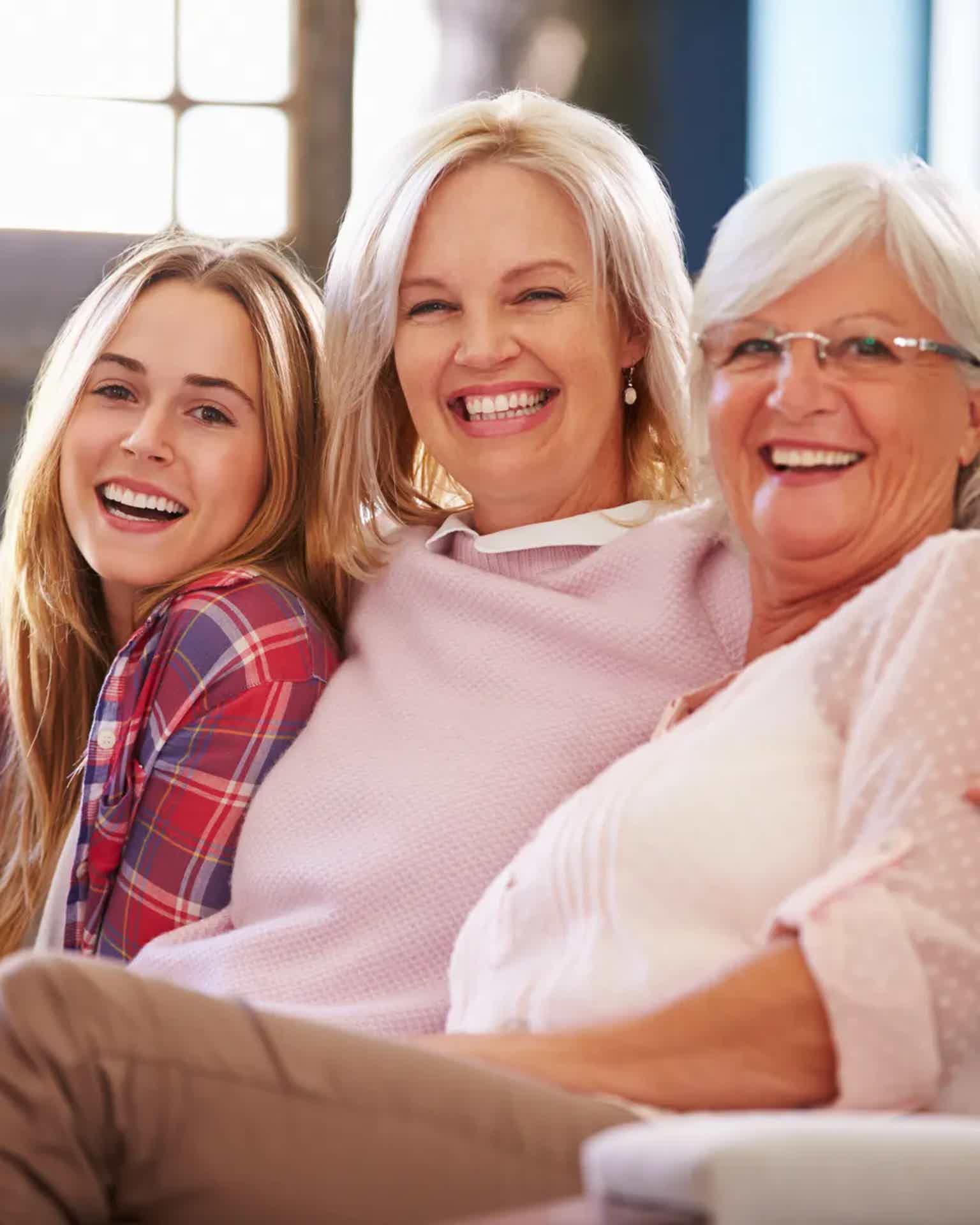 Three generations of women—grandmother, mother, and adult daughter—sitting together in Calgary, smiling and looking vibrant. They appear healthy, confident, and connected, representing different stages of life: perimenopause, menopause, and postmenopause. The scene feels natural and uplifting, with warm sunlight, soft tones, and a sense of well-being that reflects the benefits of hormone therapy and women’s health optimization at BioRevive in Calgary.