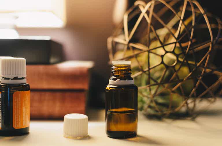 Small amber essential oil bottle with dropper cap, white cap, and a blurred warm background.