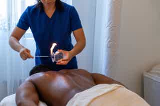 Healthcare worker in blue scrubs holding a syringe for a medical procedure on a reclining man in a clinic room