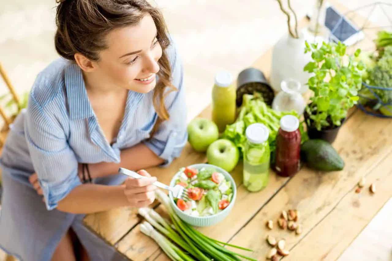 Woman eating salad with fresh fruits, vegetables, representing healthy eating and good digestion