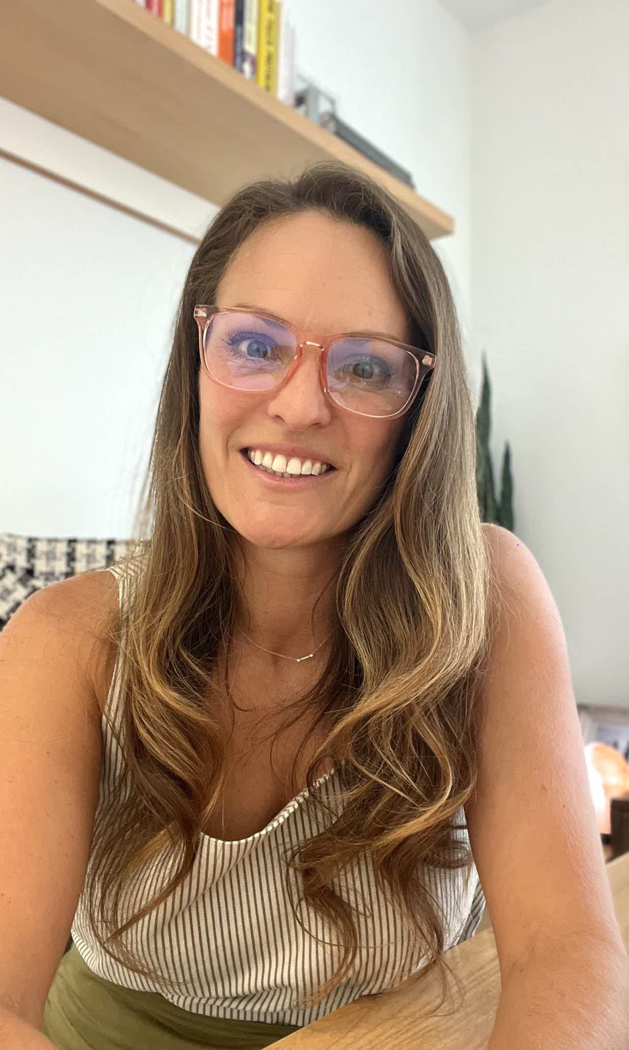 Smiling man with dark hair and full beard wearing a dark blazer and white shirt against a light background.