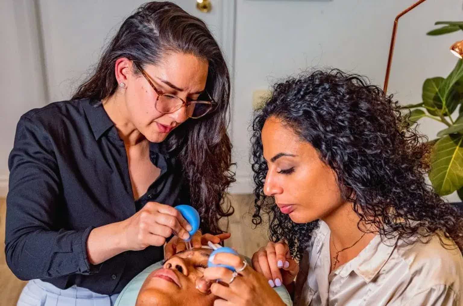 Instructor and client examining a dog’s paws with grooming tools in a bright indoor room.