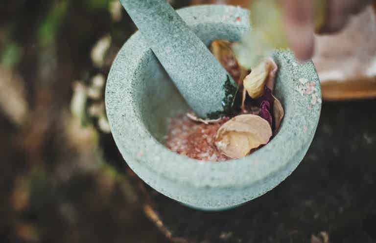 Person grinding spices in a stone mortar and pestle.