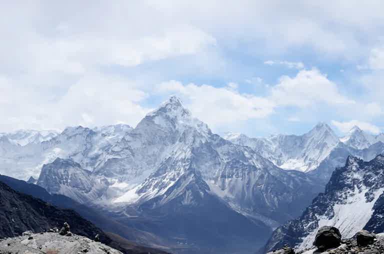 Snowy jagged mountain range under a blue sky with scattered clouds.