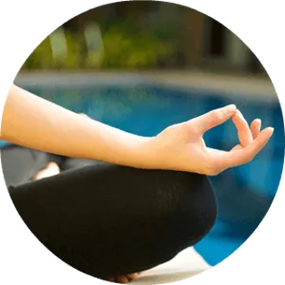 Person in a yoga lotus pose meditating by the pool.