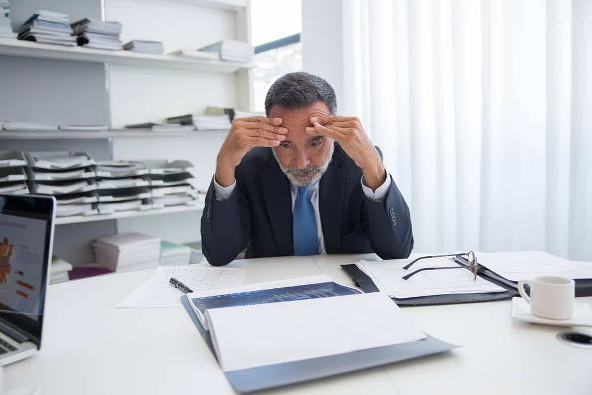 A professional holding his forehead in concentration while struggling to focus on his work, a common sign of brain fog.