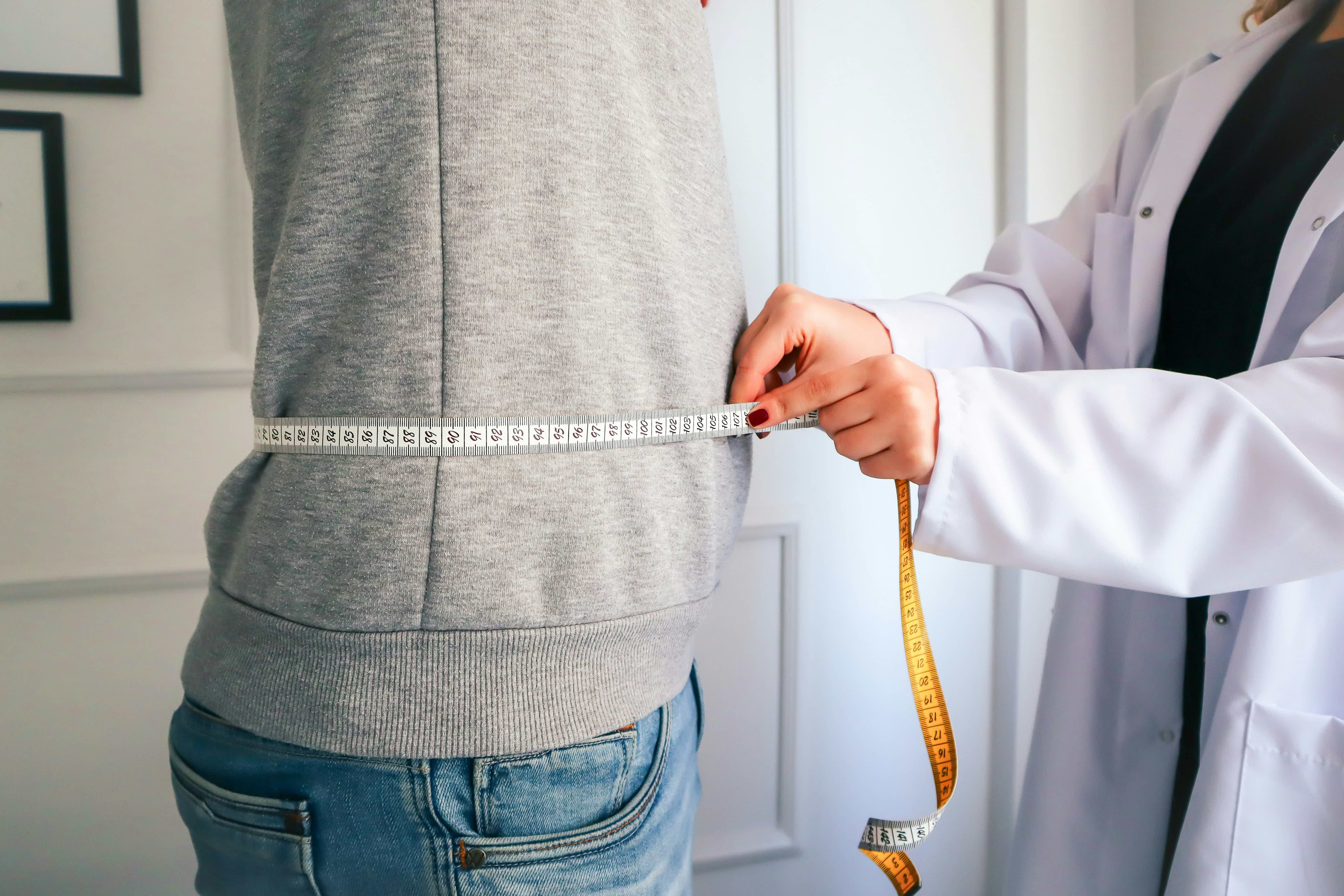 a woman measuring her waist with a measuring tape
