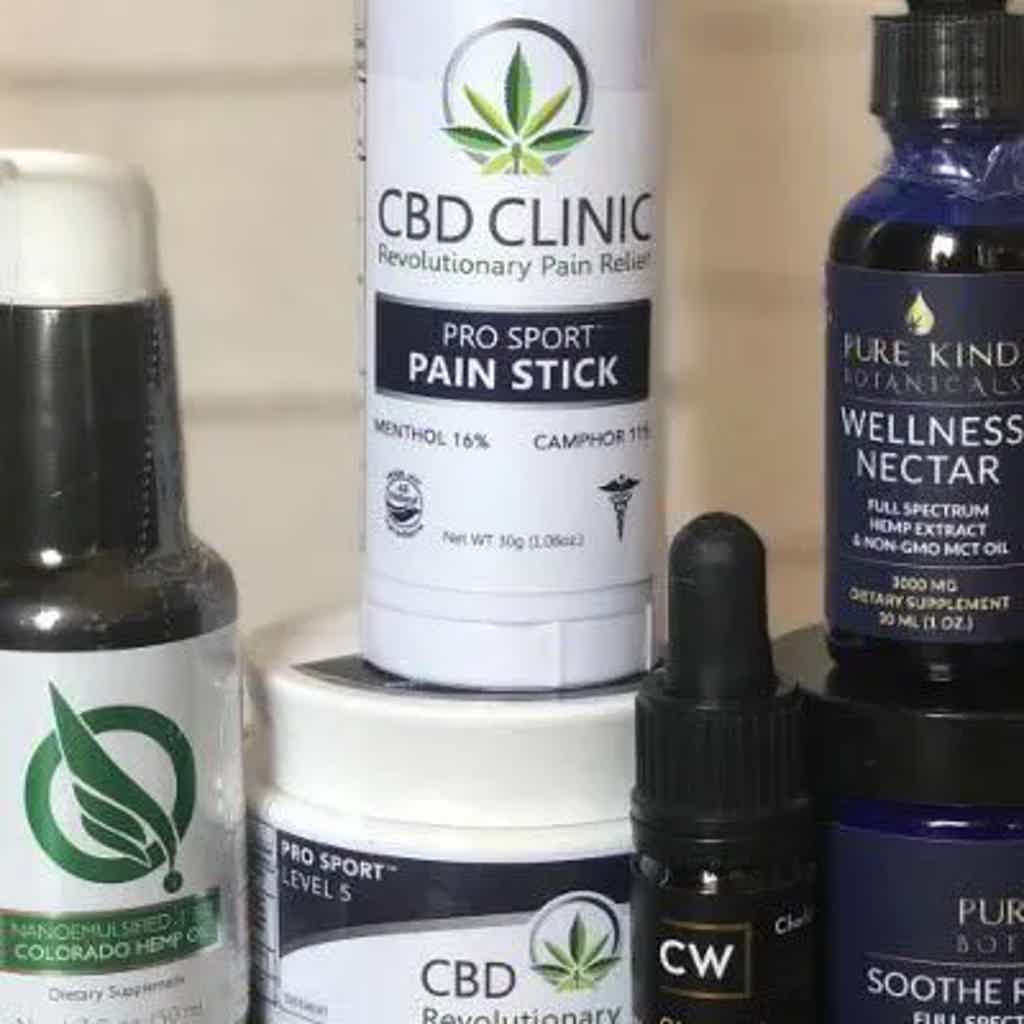 CBD Clinic pro sport pain stick, CBD oil, and wellness nectar bottles on a shelf, with CBD leaf branding.