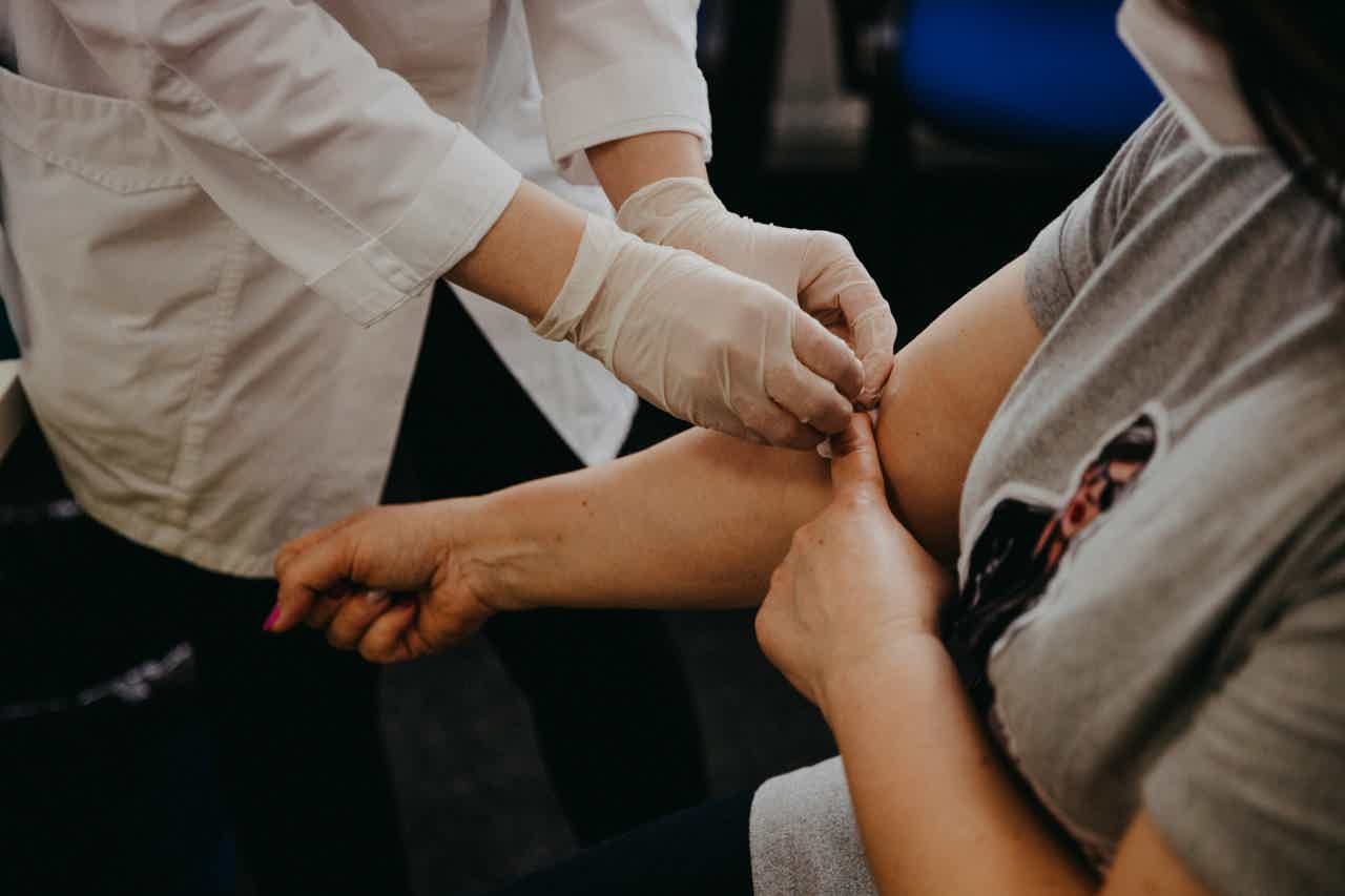 person in blue long sleeve shirt holding persons arm after a blood sample was taken