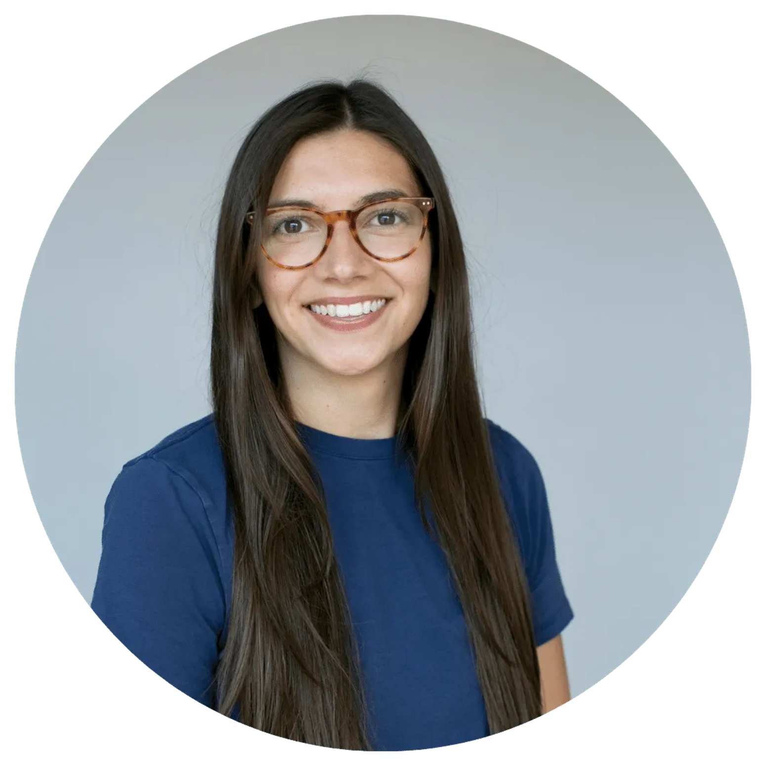 Smiling woman with long dark hair and round orange glasses against a light gray background.