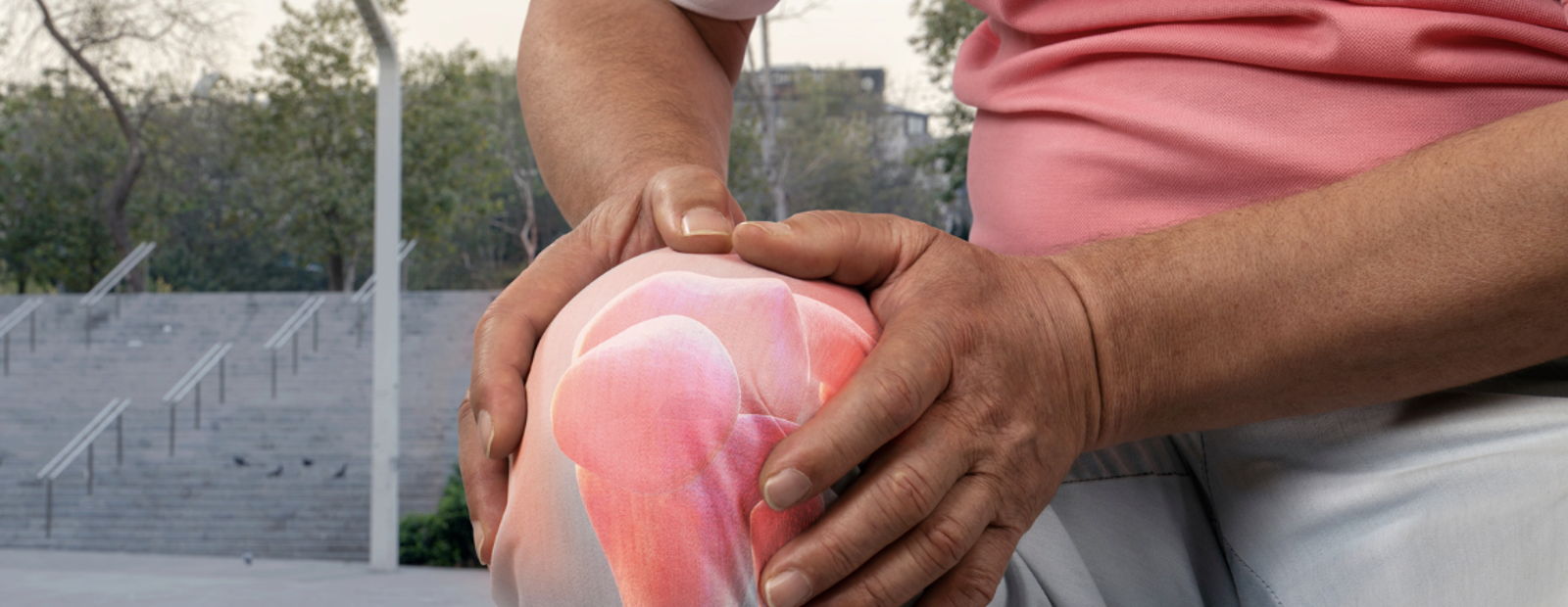 Man in pink shirt holding his knee in pain; glowing red inflammation on knee outdoors.